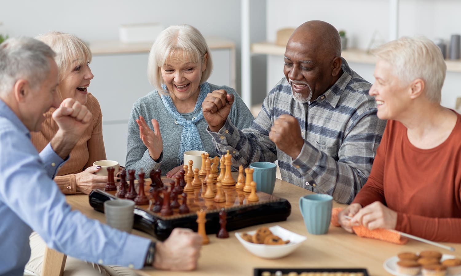 A group of seniors having fun playing chess and laughing.